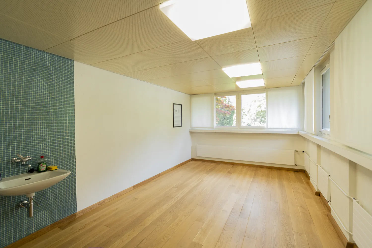 Heller Behandlungsraum mit Eichenparkett und Fensterfront